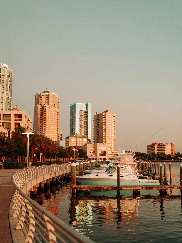 Tampa waterfront promenade at sunset with moored boats and glowing downtown towers