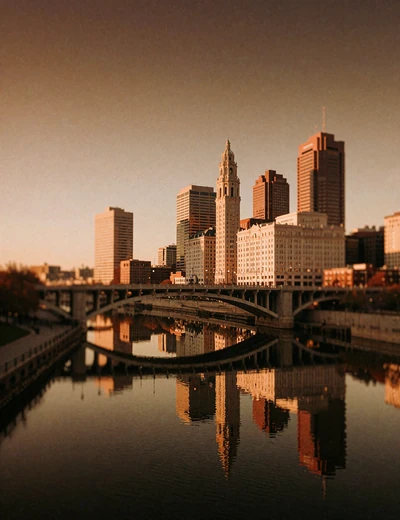 Columbus riverfront at early evening with warm-lit towers reflected in still water