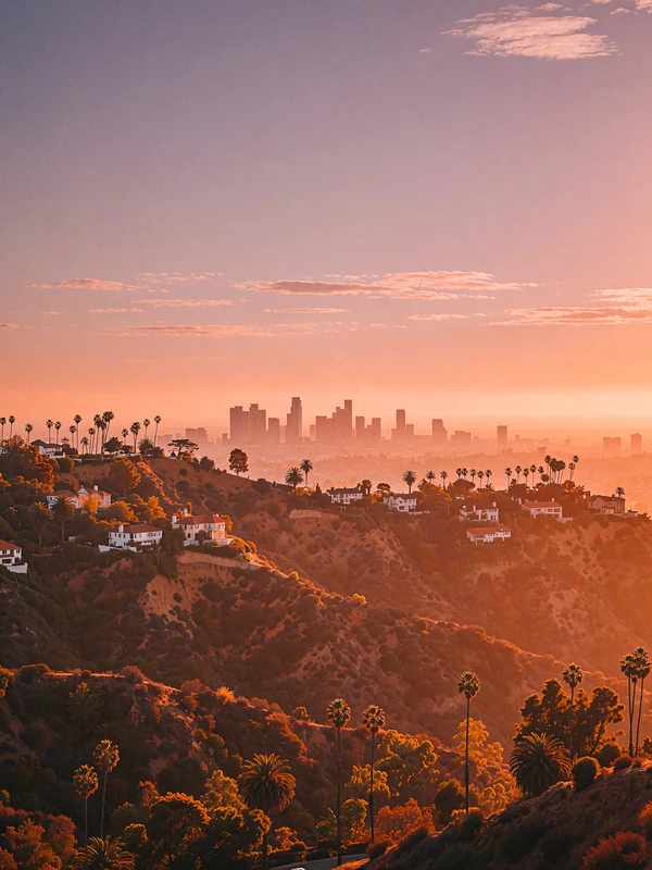 Los Angeles hills at sunset with layered ridgelines and a hazy basin of distant towers