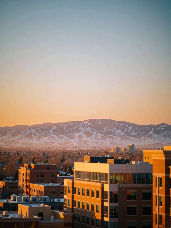 Denver skyline at sunset with a snow-touched mountain range along the horizon