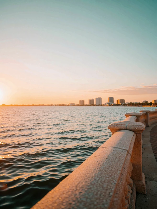 Tampa bayfront at sunset with a curved waterfront balustrade and skyline silhouettes