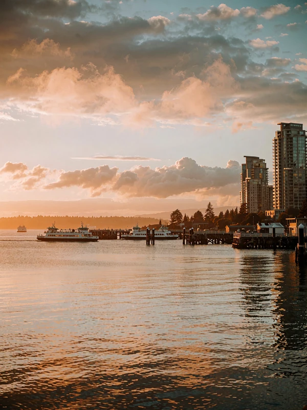 Seattle waterfront at dusk with glass towers rising above a calm amber bay